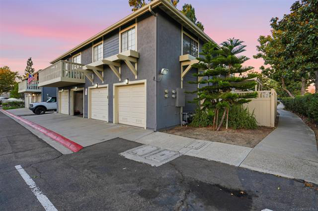 Exterior of 8837 Tamberly Ct #C in Santee at dusk, a two-story end-unit townhome with an attached garage and mature landscaping