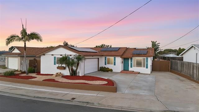 Front elevation of 5241 Jamestown Rd in Clairemont at dusk, a single-story white ranch home with teal shutters, rooftop solar panels and a palm tree in the front yard